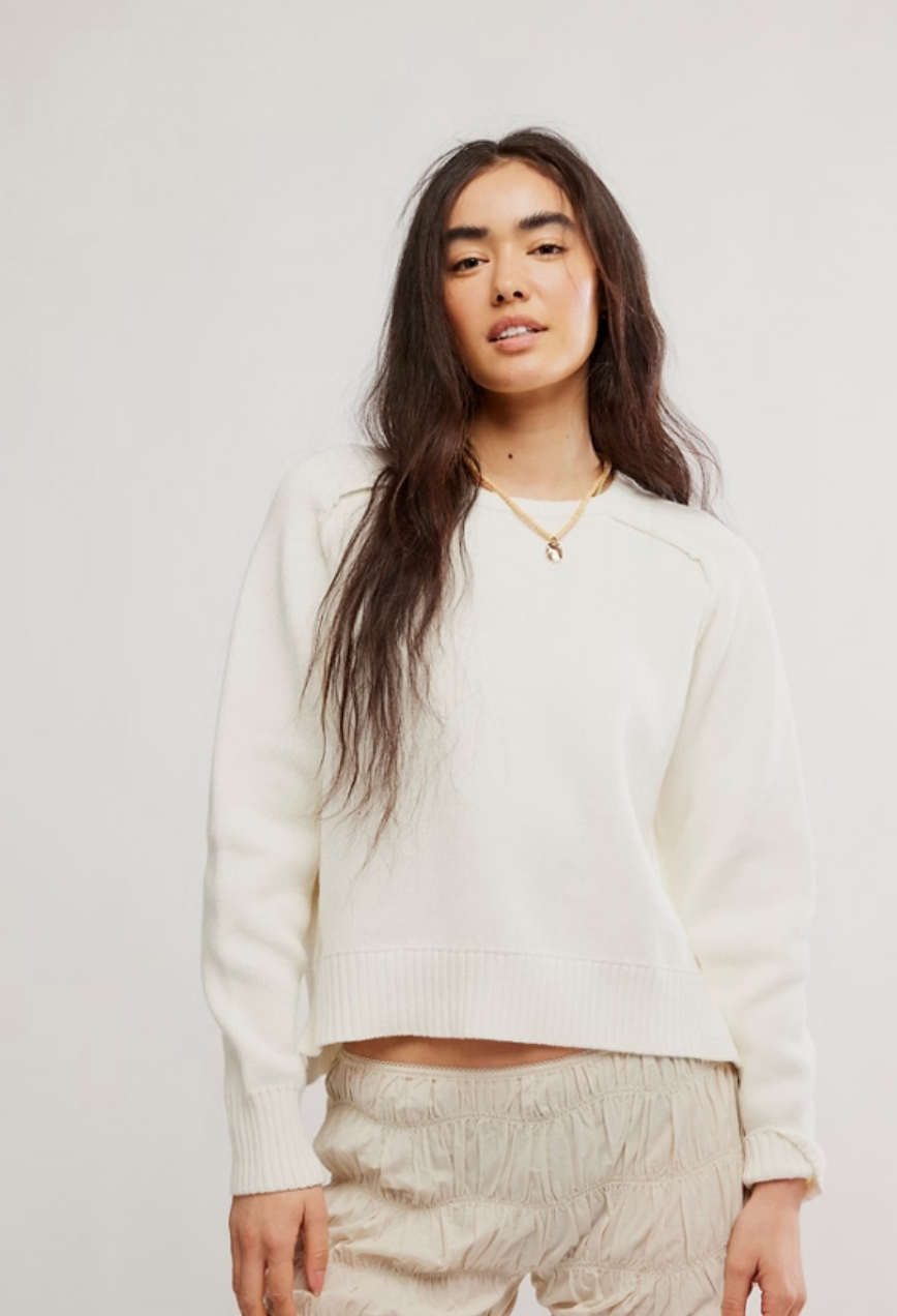 Woman wearing a white sweater and beige pants against a plain background. Free People Street Spring Pullover